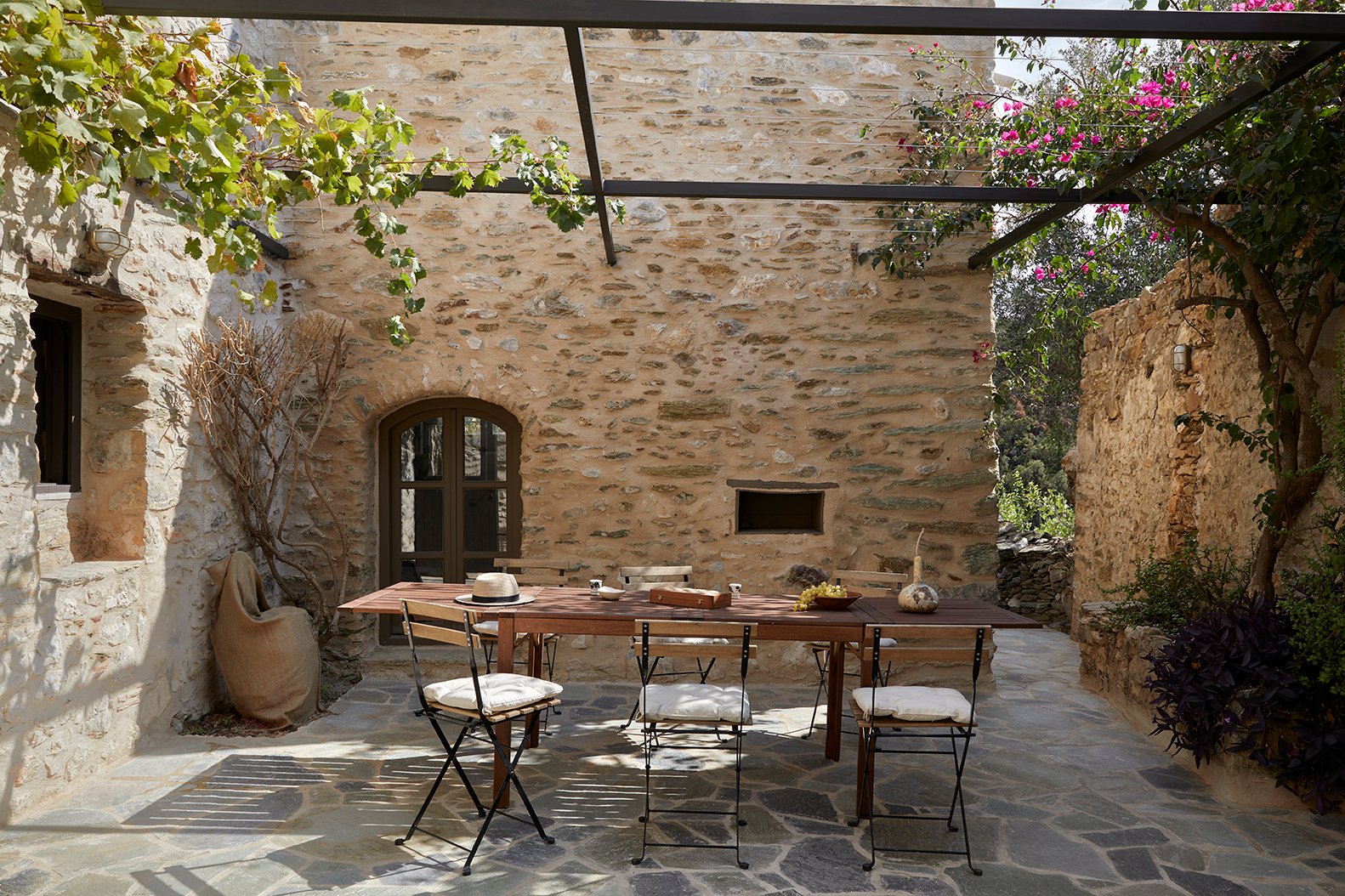 Stone courtyard with outdoor dining under a pergola, AD house, Kotroni, Mani